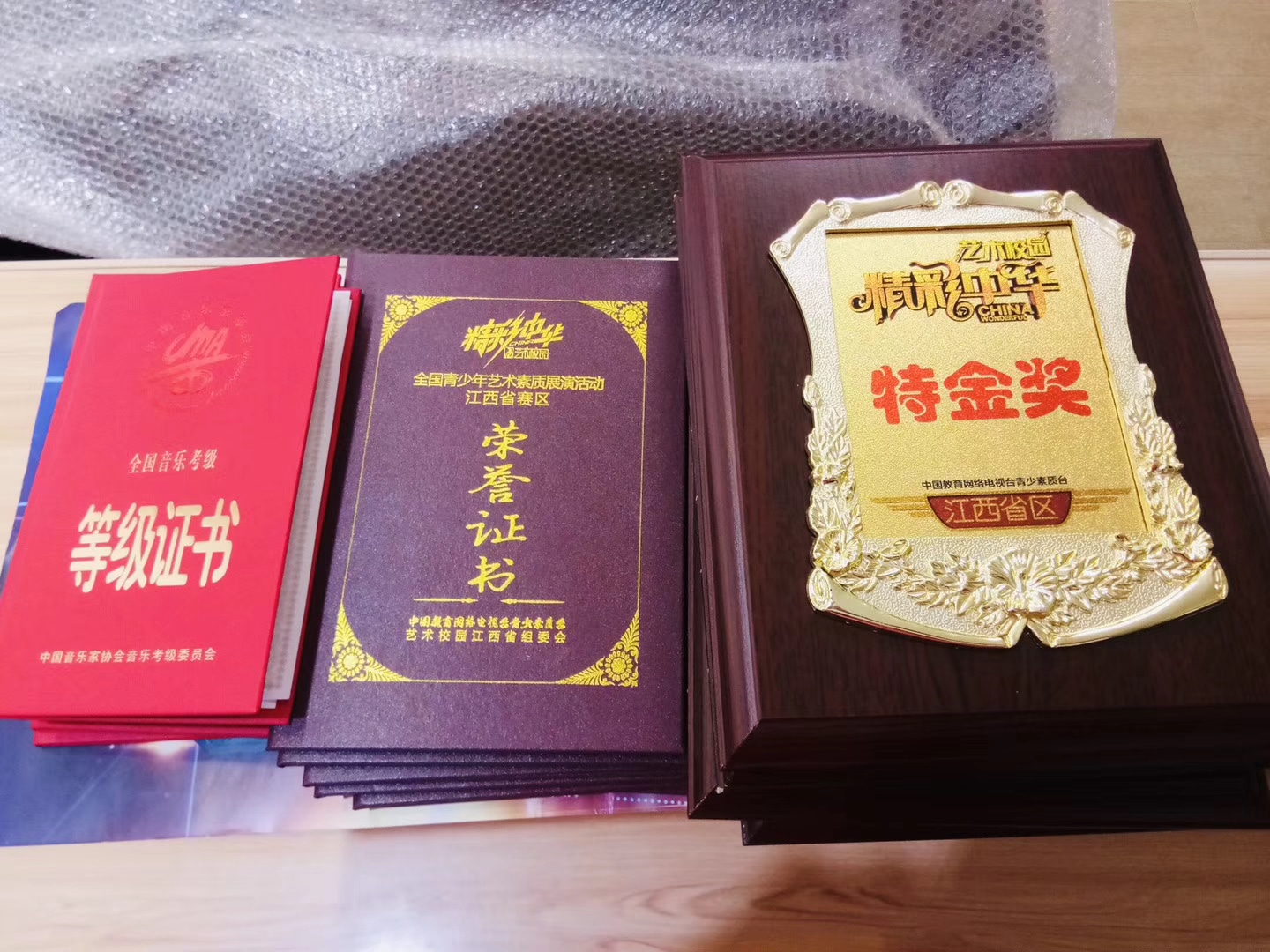 桌面陈列真实音乐考级证书、荣誉证书与比赛奖牌，完整保留奖项文字